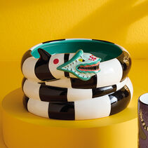 Sculpted black- and white-striped worm coiled around a bowl with its small head poised to strike