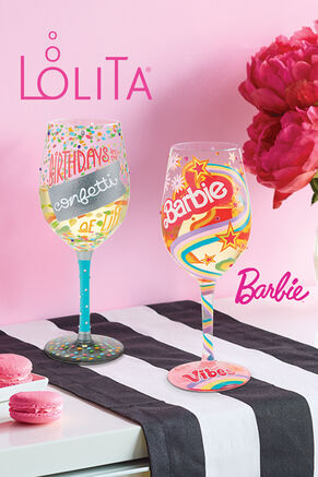 2 Lolita wine glasses on table with macarons and flowers. Birthdays are the confetti of life and Barbie.