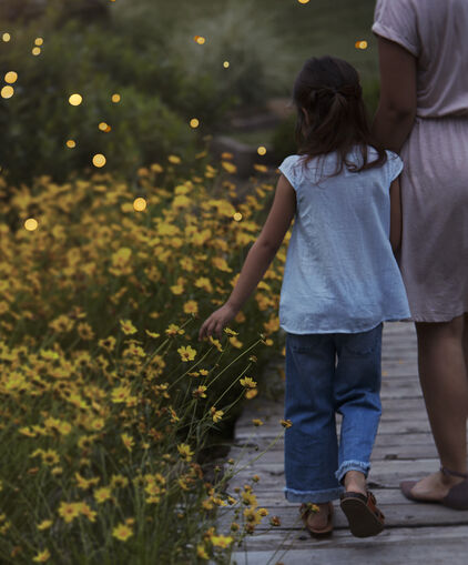 Mother and daughter walking by wildflowers