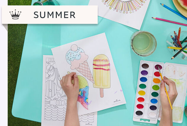 Pair of hands using watercolor to paint summer-themed coloring pages