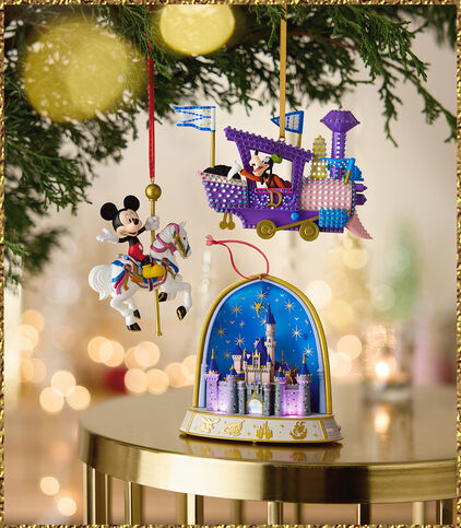 Three Disney ornaments hanging from a tree and sitting on a table