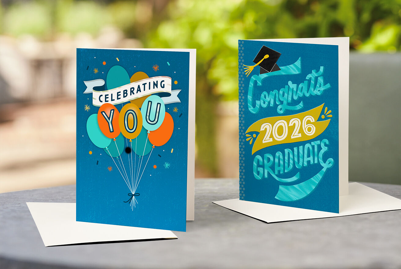 A birthday card and a graduation card on a table outdoors. 