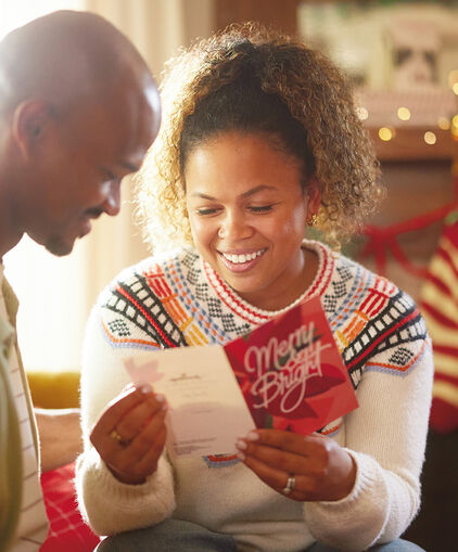 Woman reading a card while smiling beside a man.