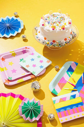 Birthday party decorations and cake on a yellow background.