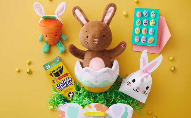 Array of Easter gifts include a plush carrot wearing bunny ears, a bunny in an egg, colored pencils, Easter greeting card and small bag with a bunny face.