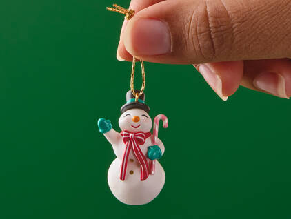 Cheerful snowman waving and holding a candy cane mini ornament