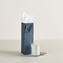 Bottle-sized gift bag next to candle.