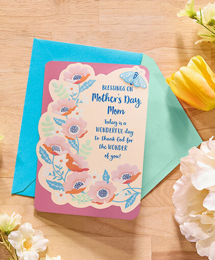 Blessing on Mothers Day greeting card on table with envelope and flowers