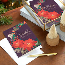 Christmas greeting cards with poinsettias and Christmas Wishes on the front in gold script on wooden table