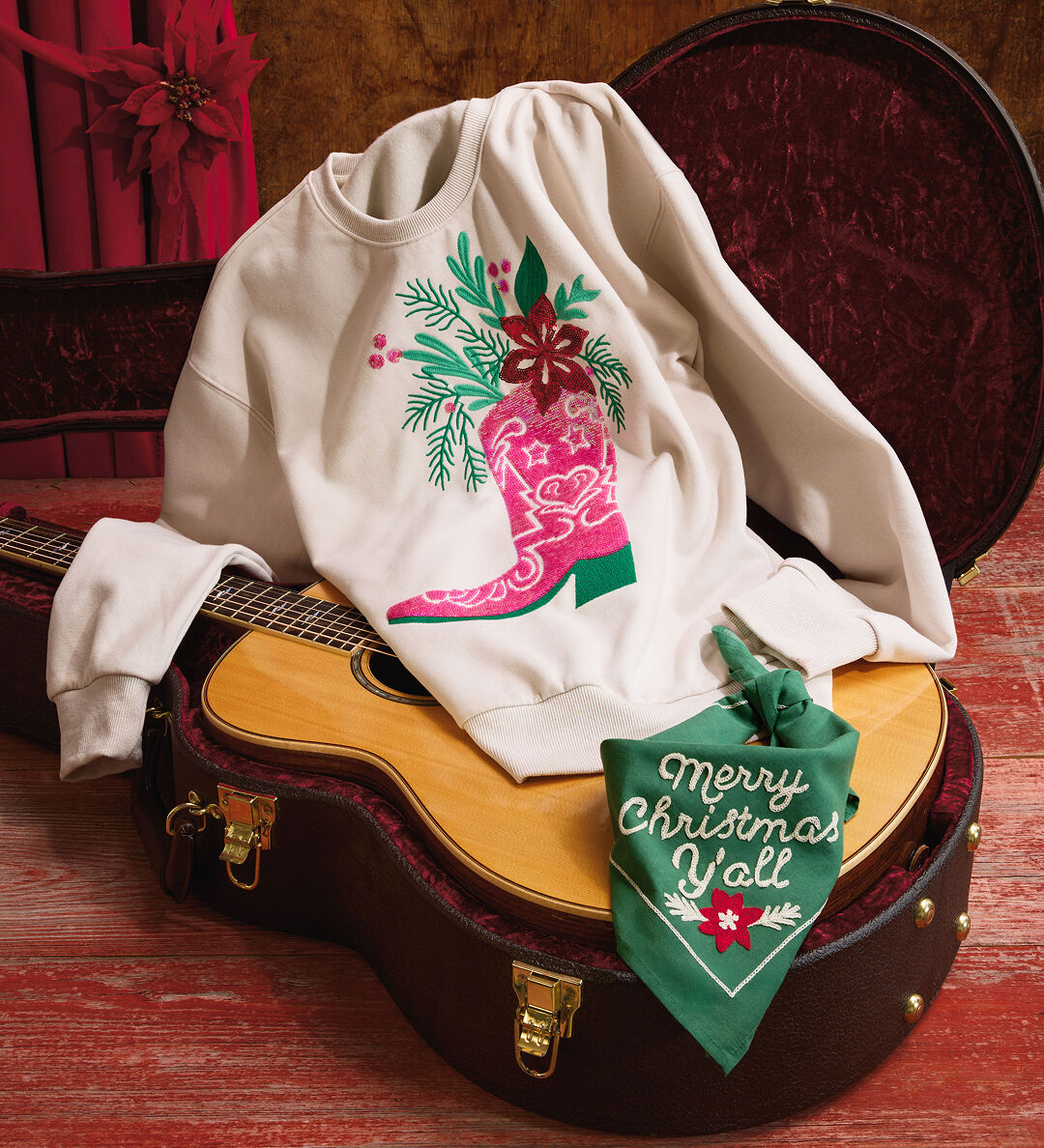 Cream-colored sweatshirt depicting a pink cowboy boot full of Christmas greenery next to a Merry Christmas Y'all' green bandana