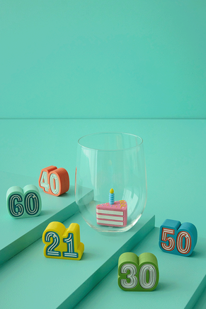 Major milestone birthday ages drink charms around a clear glass with a cake drink charm inside.