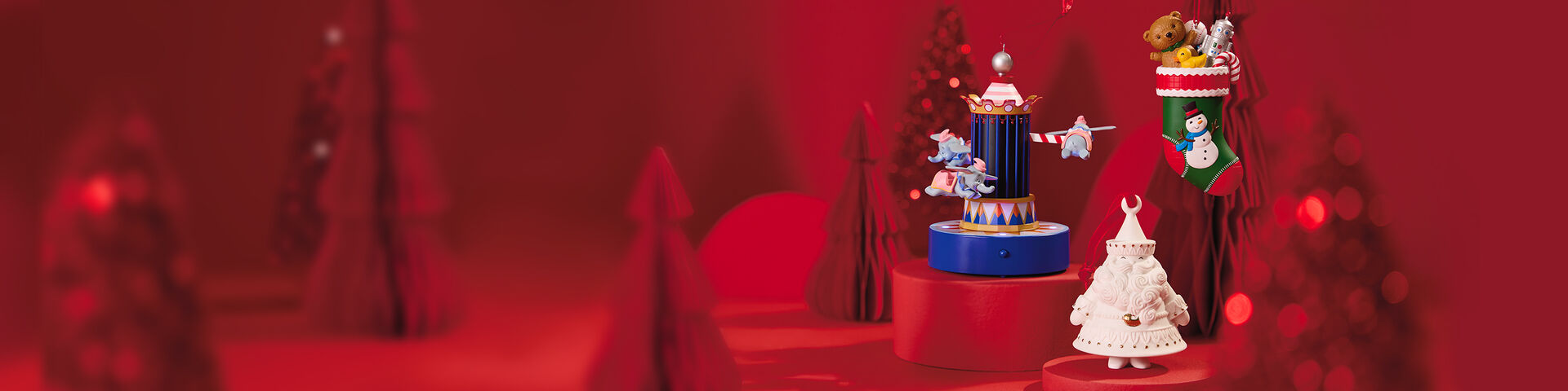 A porcelain Santa ornament, a Dumbo ornament and a stocking ornament on red stands. 