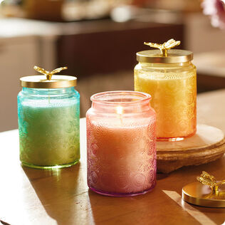 3 candles in colorful glass jars with decorative lids