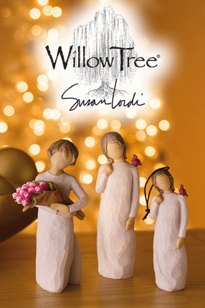 Two Willow Tree figures and a Willow Tree ornament on a wooden table.