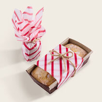 Small gift and loaf of bread wrapped in candy cane striped tissue paper.