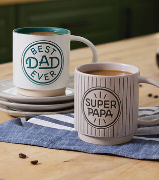 Two mugs with Fathers Day sayings on a countertop.
