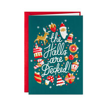 Box of greeting cards with holiday ornaments in shades of red, white, pink and gold around modern script lettering on a green background with iridescent glitter