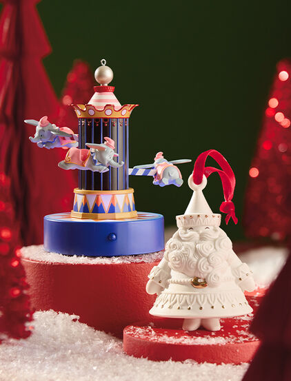 Ceramic Santa Claus and Dumbo ornaments on red stands. 