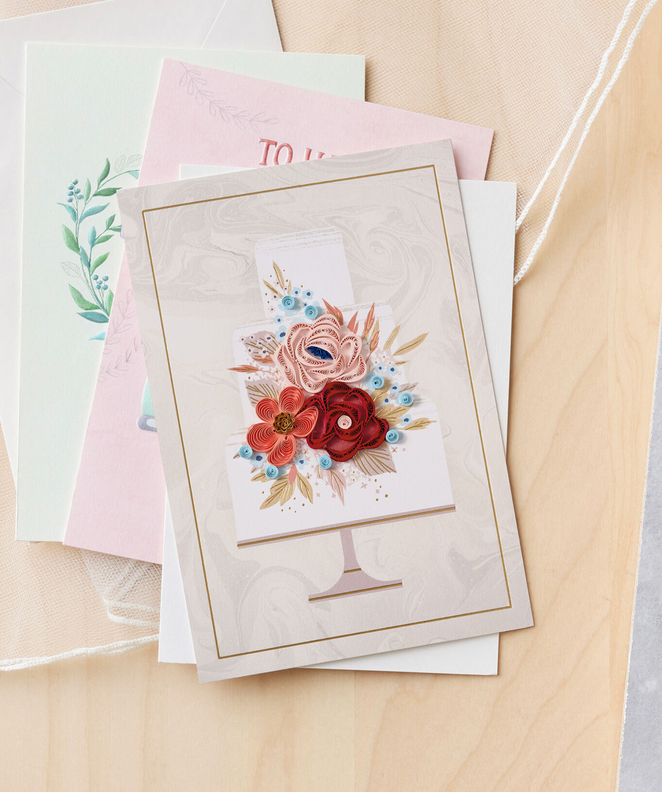 Cream card featuring paper flowers on a wedding cake. 