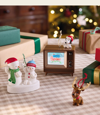 Christmas ornaments on a table and surrounded by gifts. 