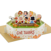 Pop-up Thanksgiving card with Snoopy, Charlie Brown, Linus, Lucy, Woodstock enjoying a feast in a pumpkin patch.