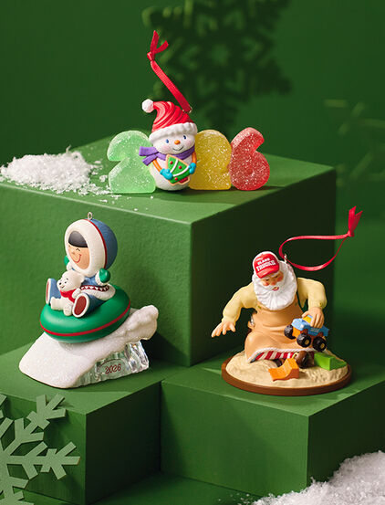 Three winter- and holiday-themed ornaments on green stands. 