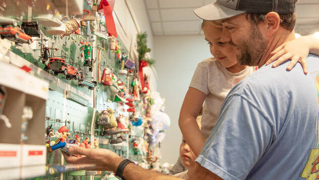 Man and kid looking at wall of ornaments