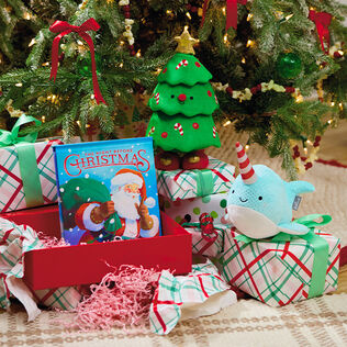 Stuffed narwhal, dancing Christmas tree toy, and Christmas picture book.