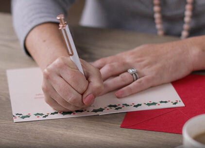 Woman writing in a Christmas card. 