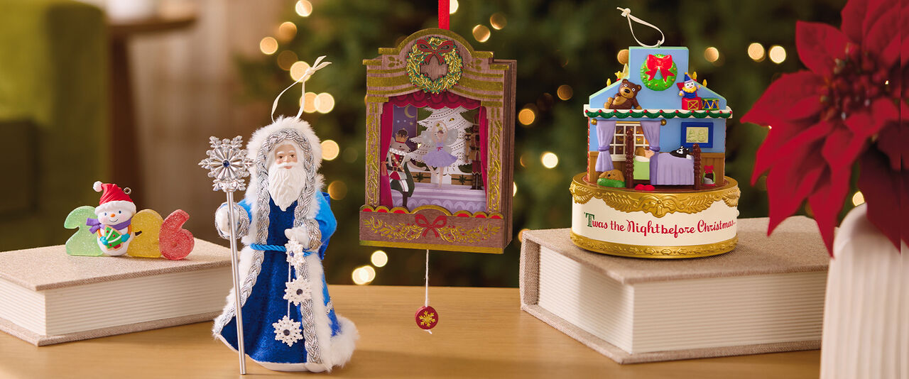 Hallmark Keepsake ornaments on table with potted poinsettia 