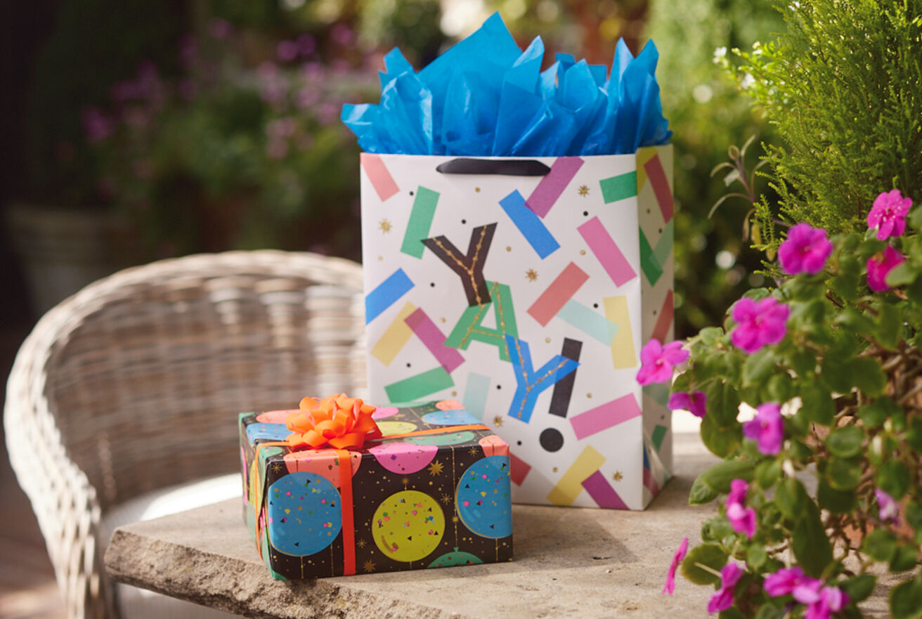 Celebratory gift wrapped present and a gift bag with blue tissue paper.