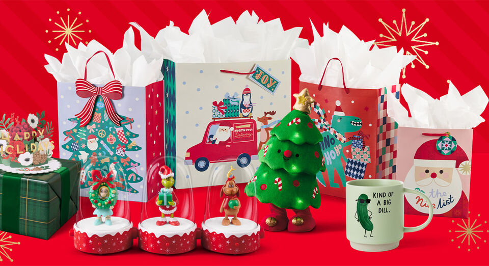 Various holiday focused gifts, gift bags, and decorations on a red background. 