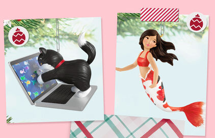 Cat playing on a laptop ornament and koi mermaid ornament.