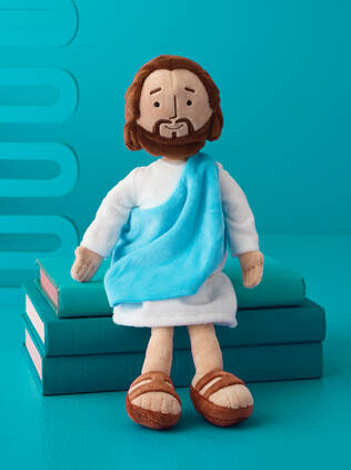 Stuffed Jesus plush on cyan books on a cyan background.