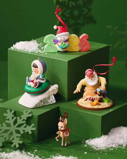 Multiple winter-themed ornaments on a dark green background.