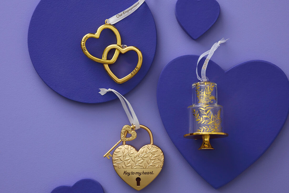 Golden linked hearts ornament, wedding cake ornament and heart lock ornament on purple background.