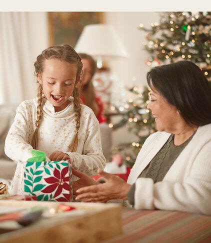 Woman giving her daughter a wrapped gift to open. 
