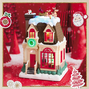 Up on the Housetop table decoration in front of red cone tree decor with paper cut-out ornaments.
