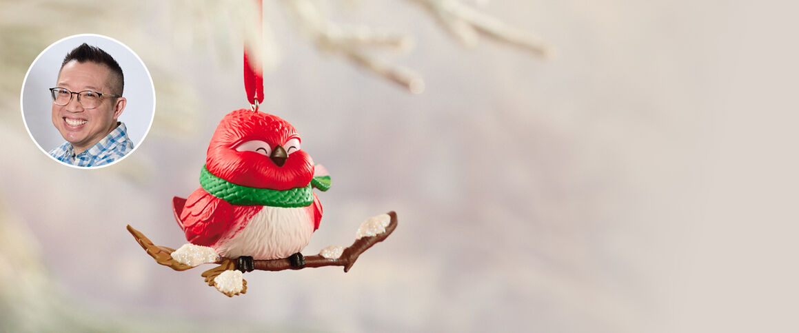 Chubby cardinal wearing a green scarf sitting on a branch ornament. 