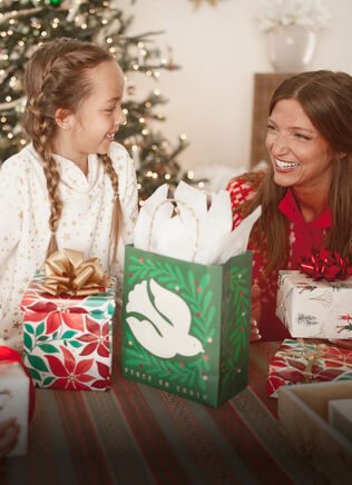 Mother and daughter smiling over a pile of presents on a table.
