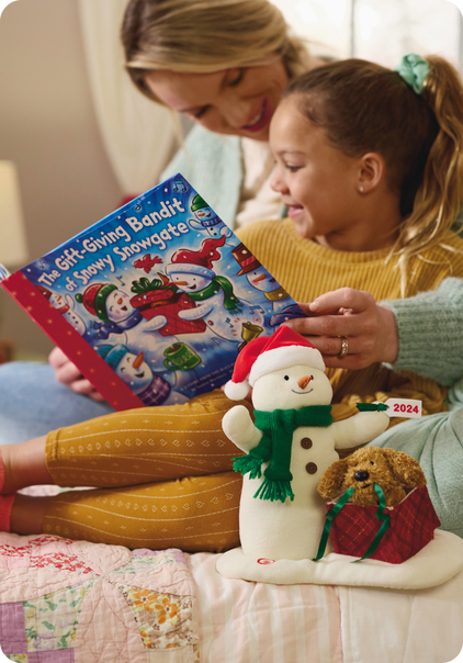Mom and daughter read 2024 snowman book with singing and dancing snowman stuffed animal beside them.