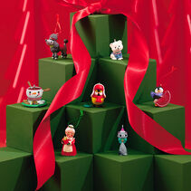 7 miniature Keepsake Ornaments on green boxes with red ribbon