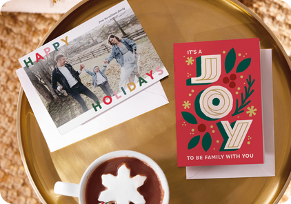 Two personalized holiday card designs on a table.
